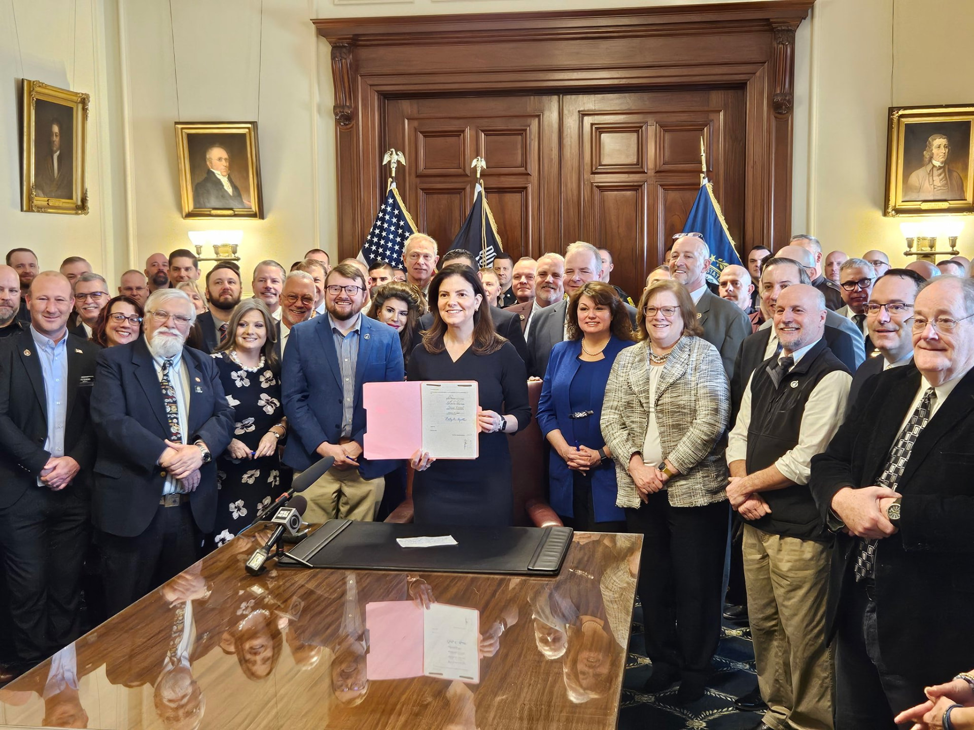Sharon Carson with a large group of legislators and law enforcement officers at a bill signing